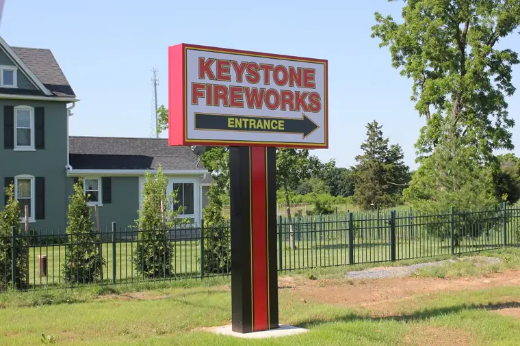 Red Keystone entrance sign with an arrow at the road